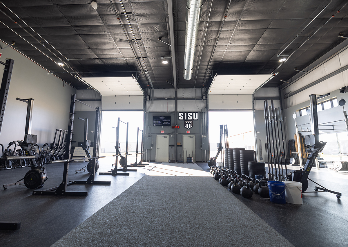 SISU workout area with rowers, weights and rigs with two large garage doors open in background